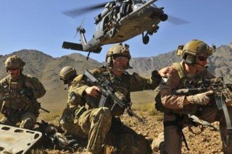 US Air Force Pararescue Jumpers (PJs) deployed, helicopter taking off in the background