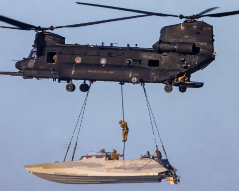 one of an MH-47 Chinook sling loading a stealthy Combat Craft Assault (CCA) boat while one of its crew, most likely a SWCC, fast ropes down into it in mid-air.