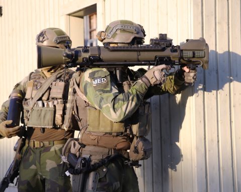 Two soldiers aiming a Carl-Gustaf M4 recoilless rifle from behind cover