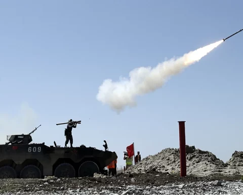 Soldier fires a 9K38 Igla missile from the shoulder while standing on an armored personnel carrier.