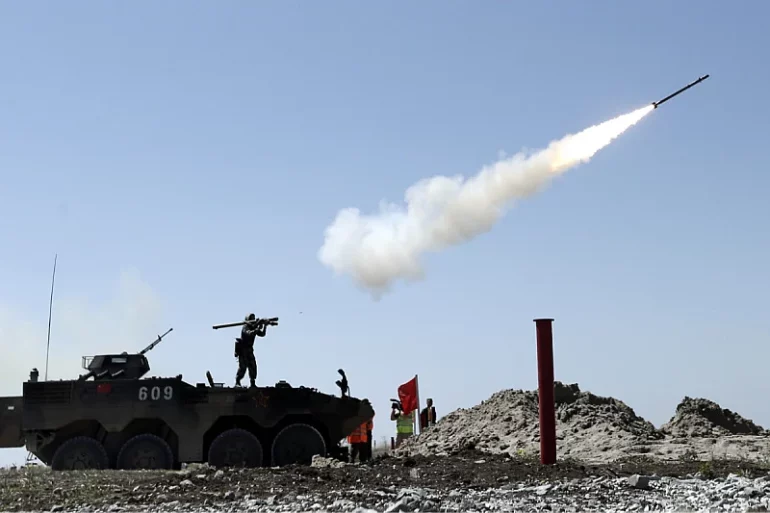 Soldier fires a 9K38 Igla missile from the shoulder while standing on an armored personnel carrier.