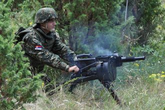 Serbian soldier firing Zastava M93 BGA automatic grenade launcher in a field setting