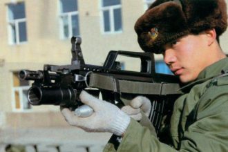 A Chinese soldier hodling an assault rifle with mounted QLG-10 underbarrel grenade launcher