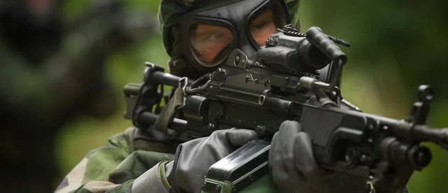Swedish soldier with Kulspruta 90B machine gun wearing Skyddsmask 90 gas mask during training
