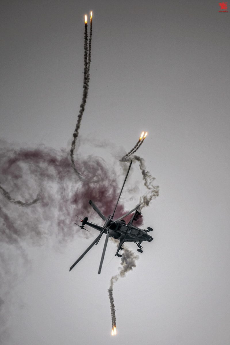 CAIC Z-10 attack helicopter in flight deploying defensive flares during evasive maneuvers.