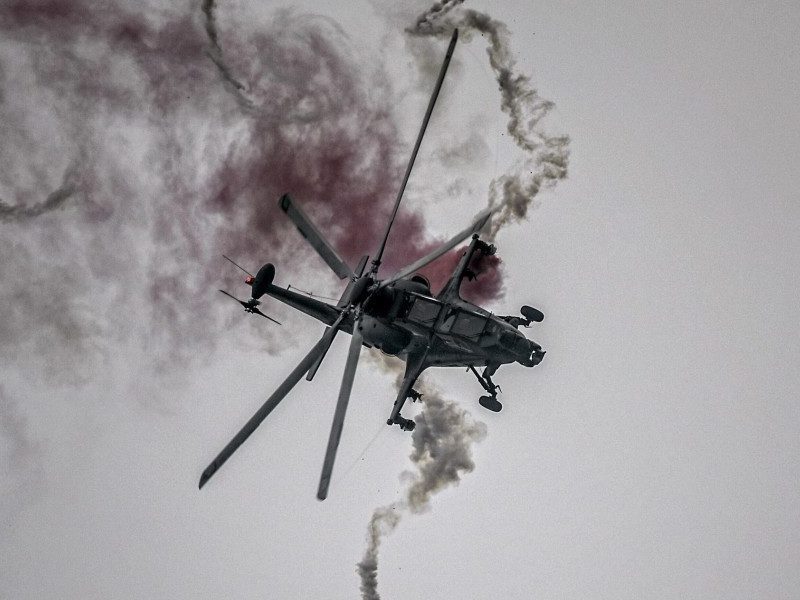 CAIC Z-10 attack helicopter in flight deploying defensive flares during evasive maneuvers.